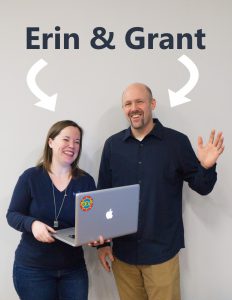 Erin (left) holds a laptop and stands next Grant (right) who is waving. Both are in blue shirts.